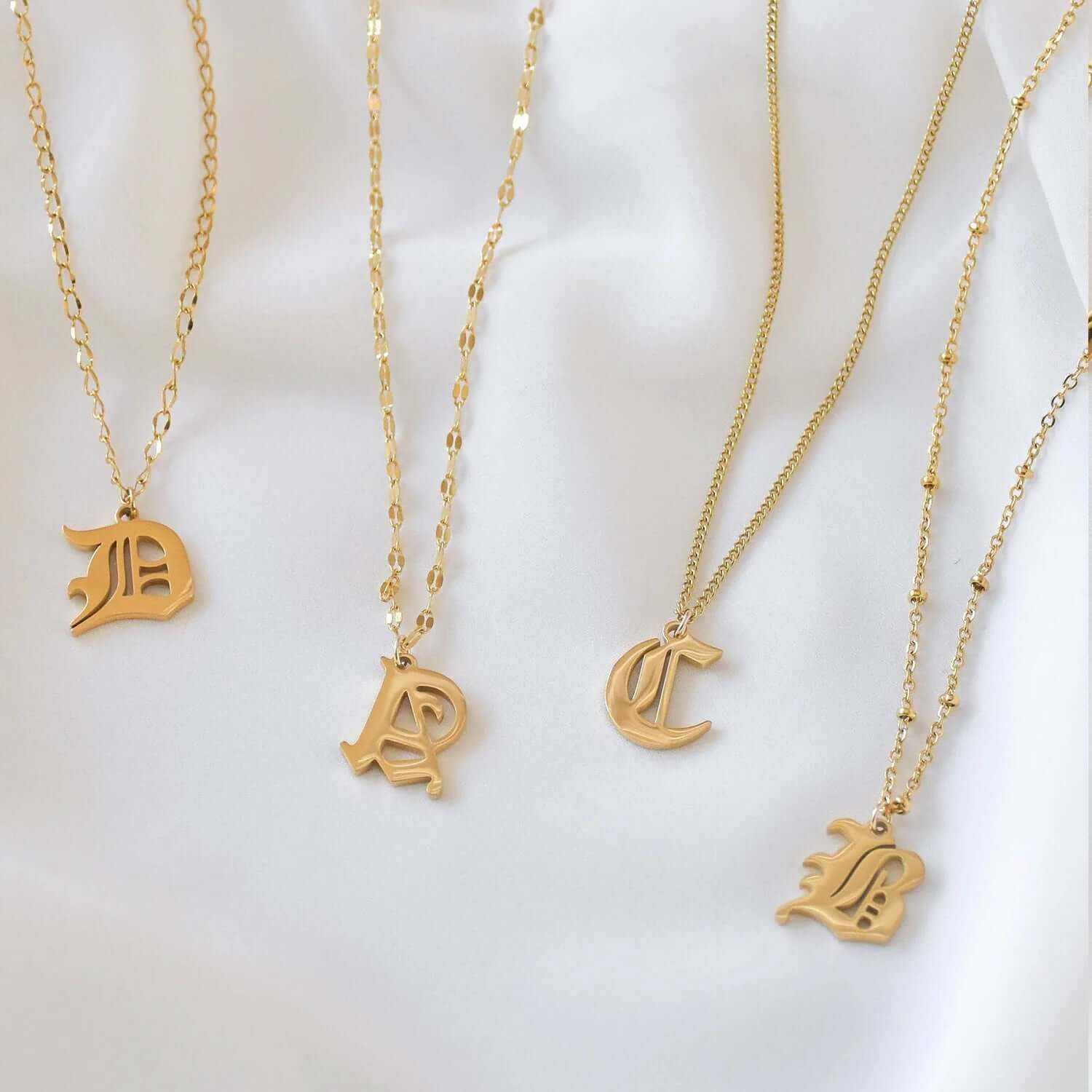 Four 18K gold plated gothic initial necklaces featuring letters D, R, C, and B on delicate chains.