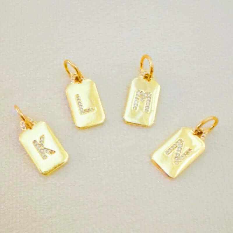 Four custom square initial seamless clip charms in gold, featuring initials K, L, M, and N with sparkly cubic zirconia.