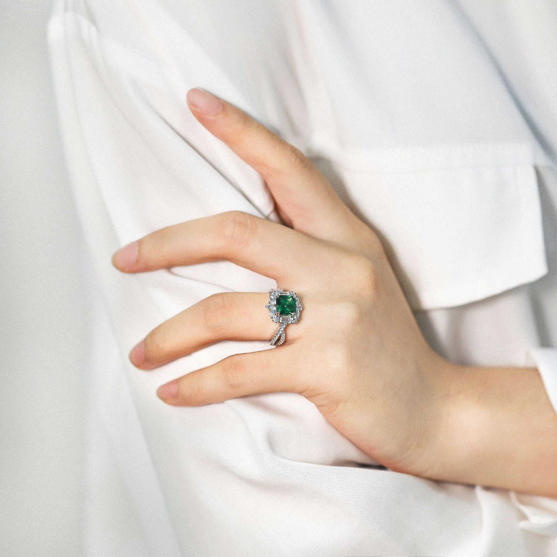 European style grandmother engagement ring with green gemstone and silver band on hand
