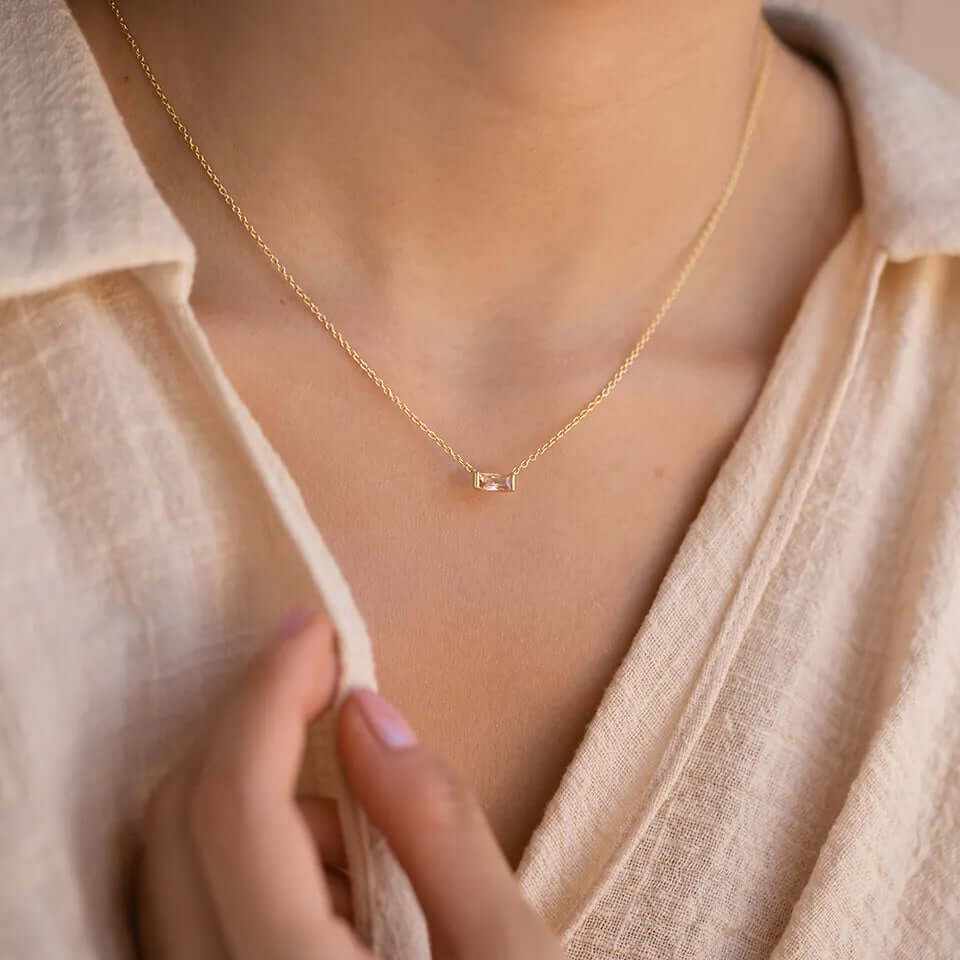 Dainty 18K gold-plated baguette birthstone necklace worn on a model's neck, showcasing elegance and style.