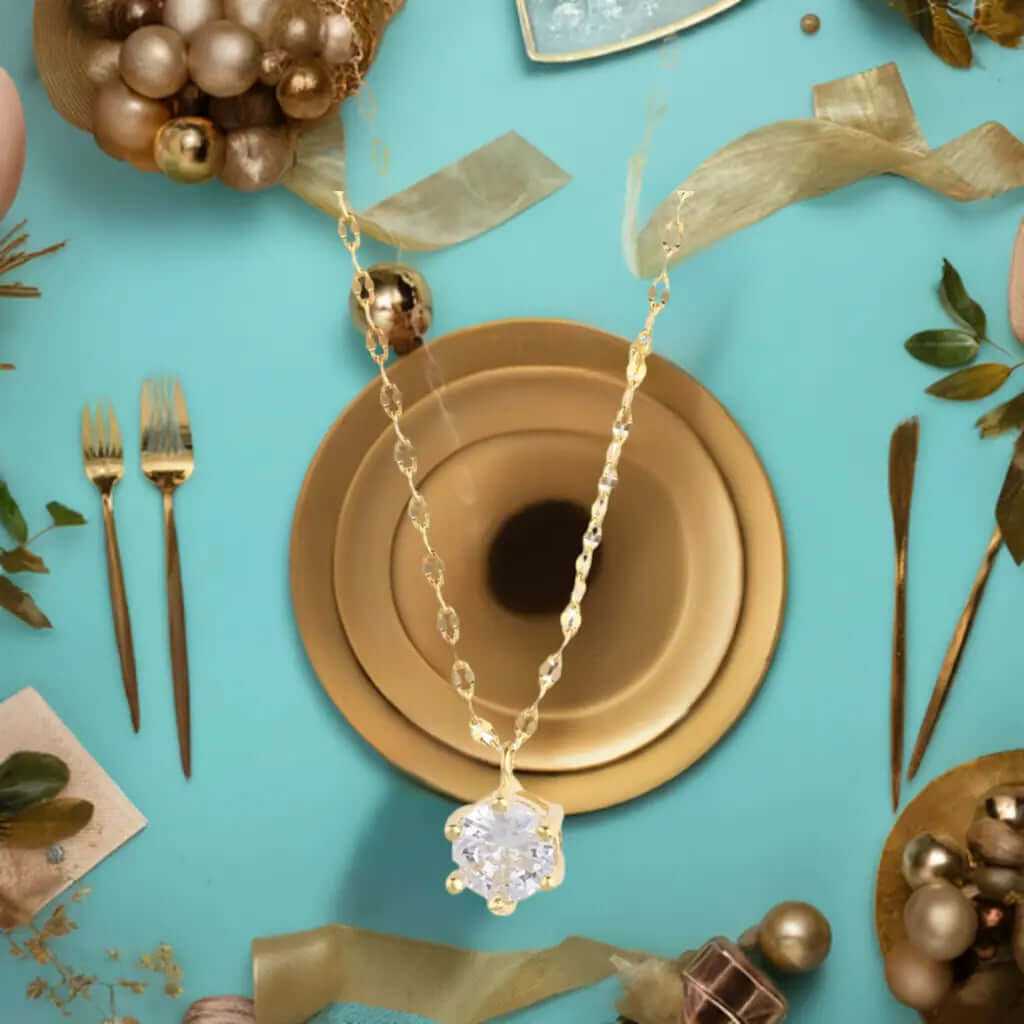 Dainty 14K gold plated solitaire necklace with cubic zirconia on a stylish dining table setting.