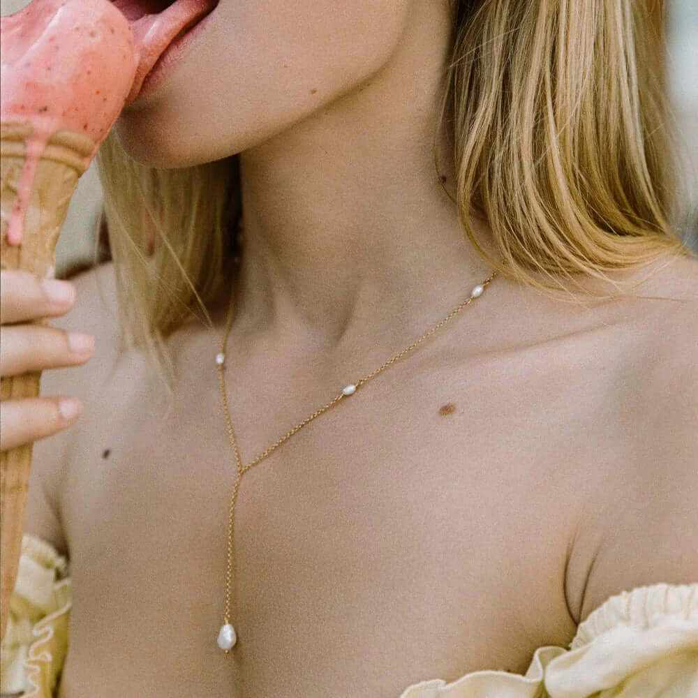 Dainty freshwater pearl necklace on a woman enjoying ice cream, showcasing elegance and style.