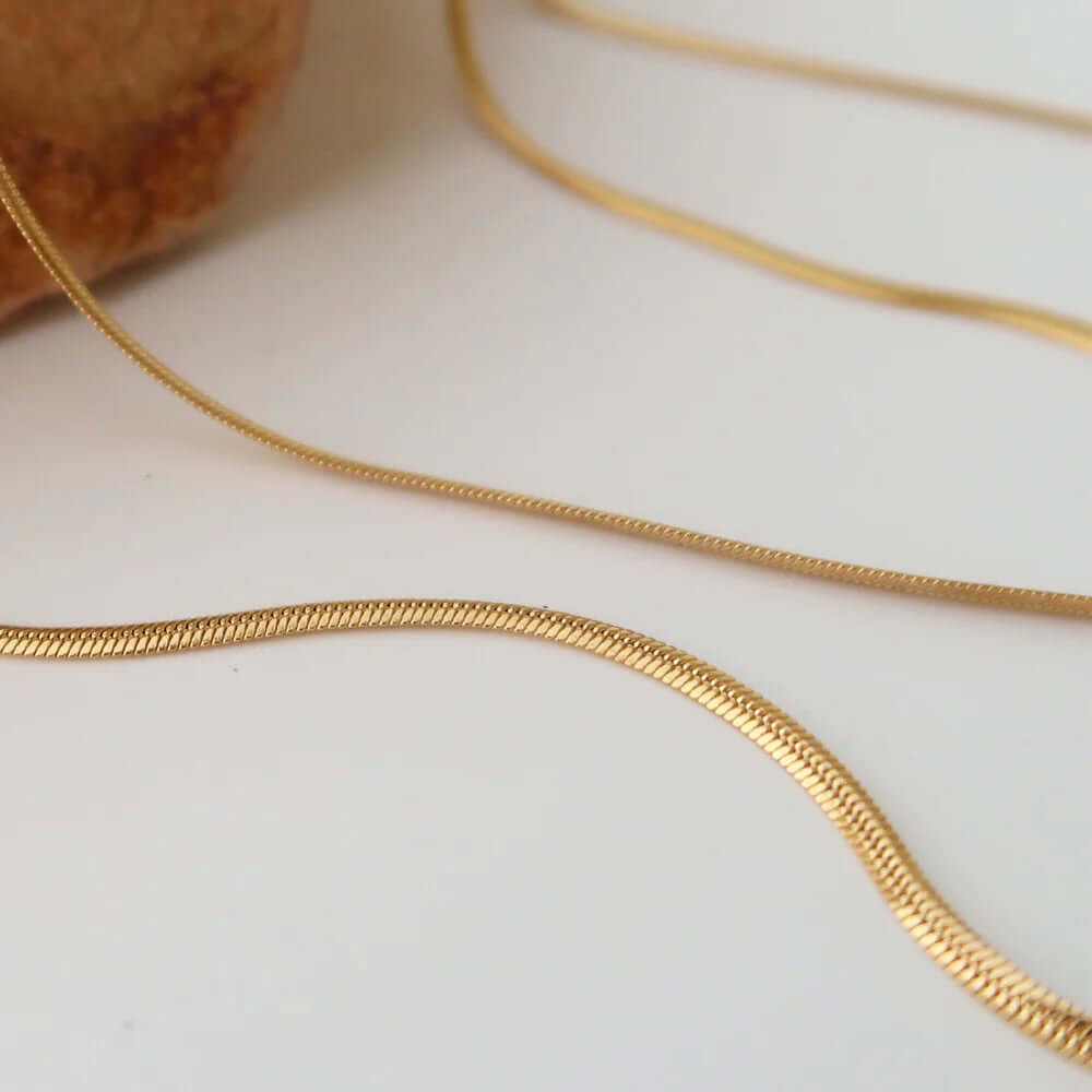 Close-up of dainty layered gold plated choker necklace showcasing elegant gold chains on a minimalist background.