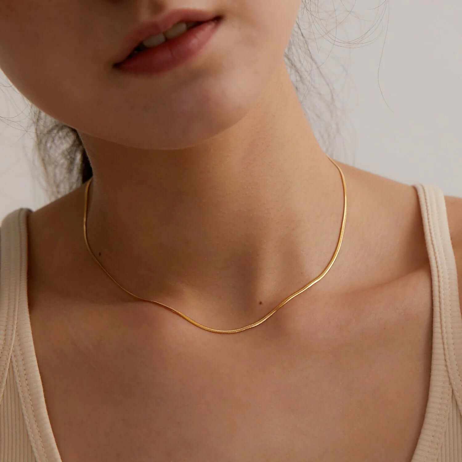 Close-up of a woman wearing a dainty layered gold plated choker necklace, showcasing elegance and sophisticated style.
