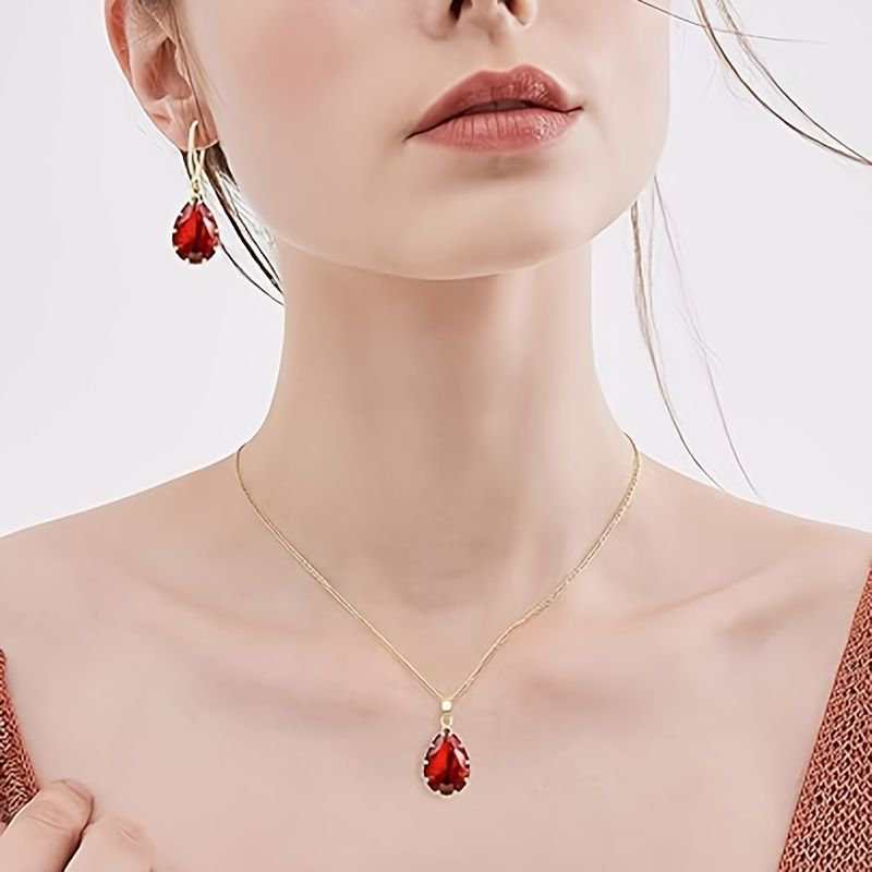 woman wearing dazzling rose gold necklace and earrings set with red teardrop gemstones