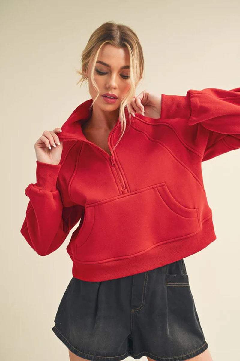Model wearing a red half-zip sweater with a cozy funnel neck and relaxed fit, styled with a denim skirt.