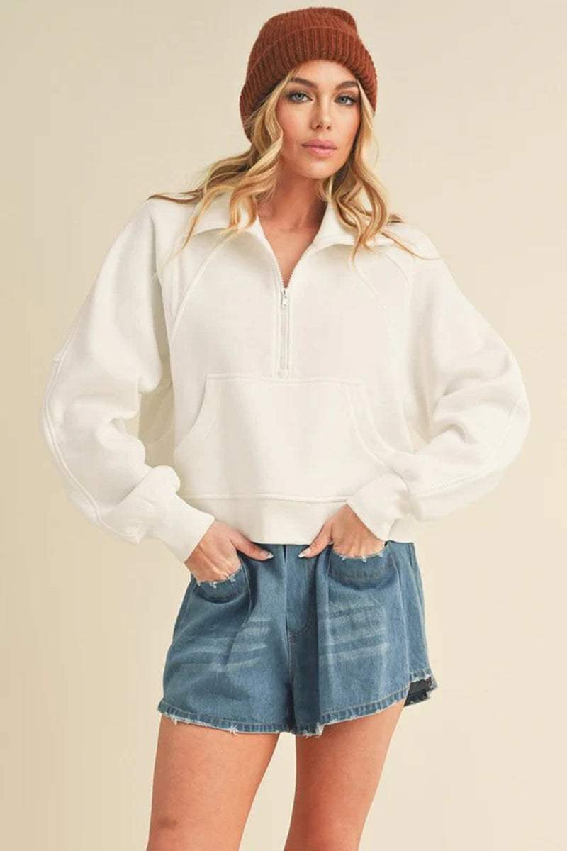 Dove half-zip sweater in white with cozy funnel neck, styled with denim shorts and a brown beanie, perfect for casual outings.