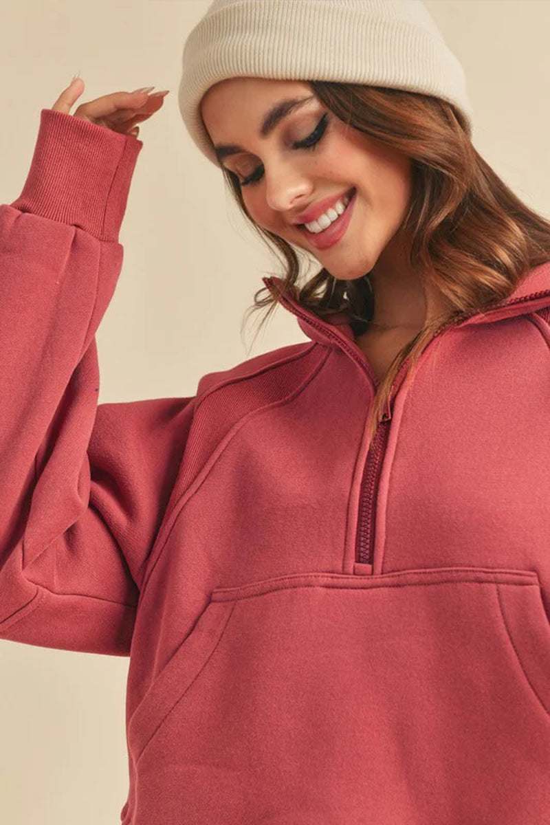 Smiling woman in a cozy dove half-zip sweater with funnel neck and oversized fit, wearing a cream beanie.