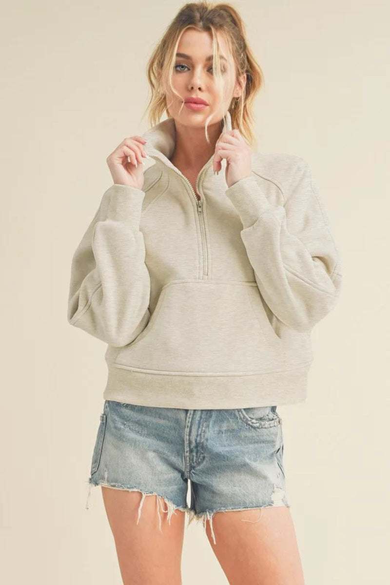 Dove half-zip sweater styled with denim shorts for a comfy, casual look, showcasing its oversized fit and cozy funnel neck.