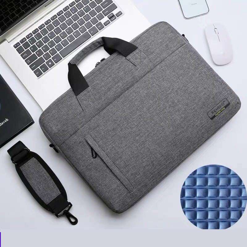 Waterproof shoulder bag for laptops resting on a desk with a laptop and mouse, showcasing its sleek design.