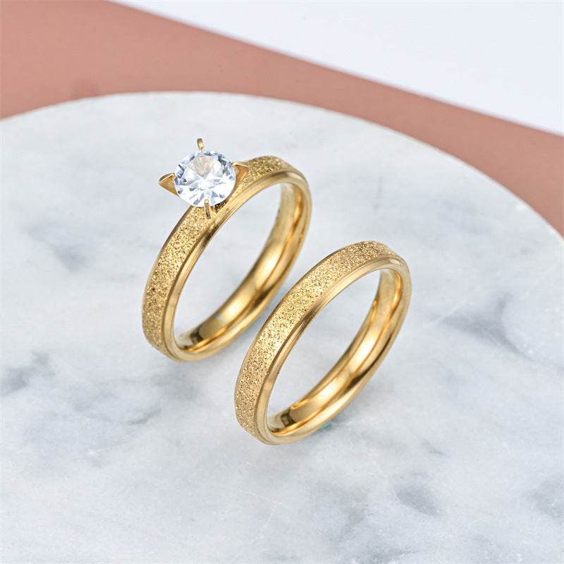 Fashionable elegant gold stainless steel couple rings with a clear gemstone on one ring
