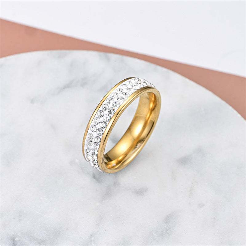 Fashionable elegant stainless steel gold-tone ring with clear crystals on marble background