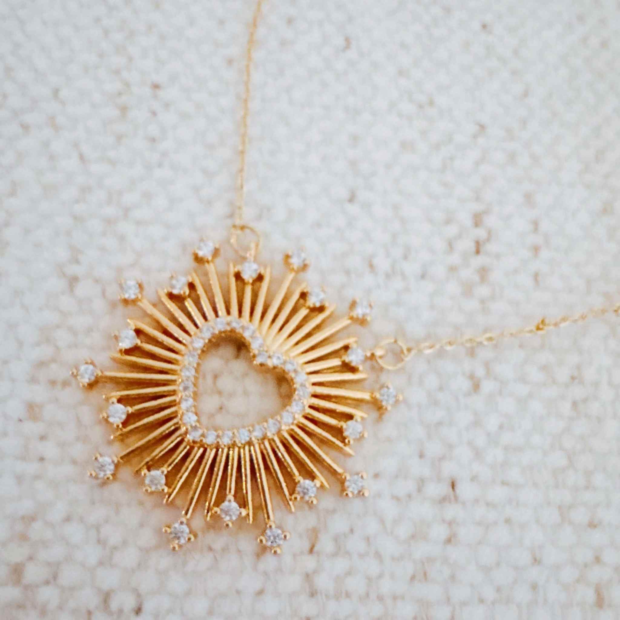Elegant heart pendant necklace with sunburst design and sparkling accents, perfect for adding glam to any outfit.