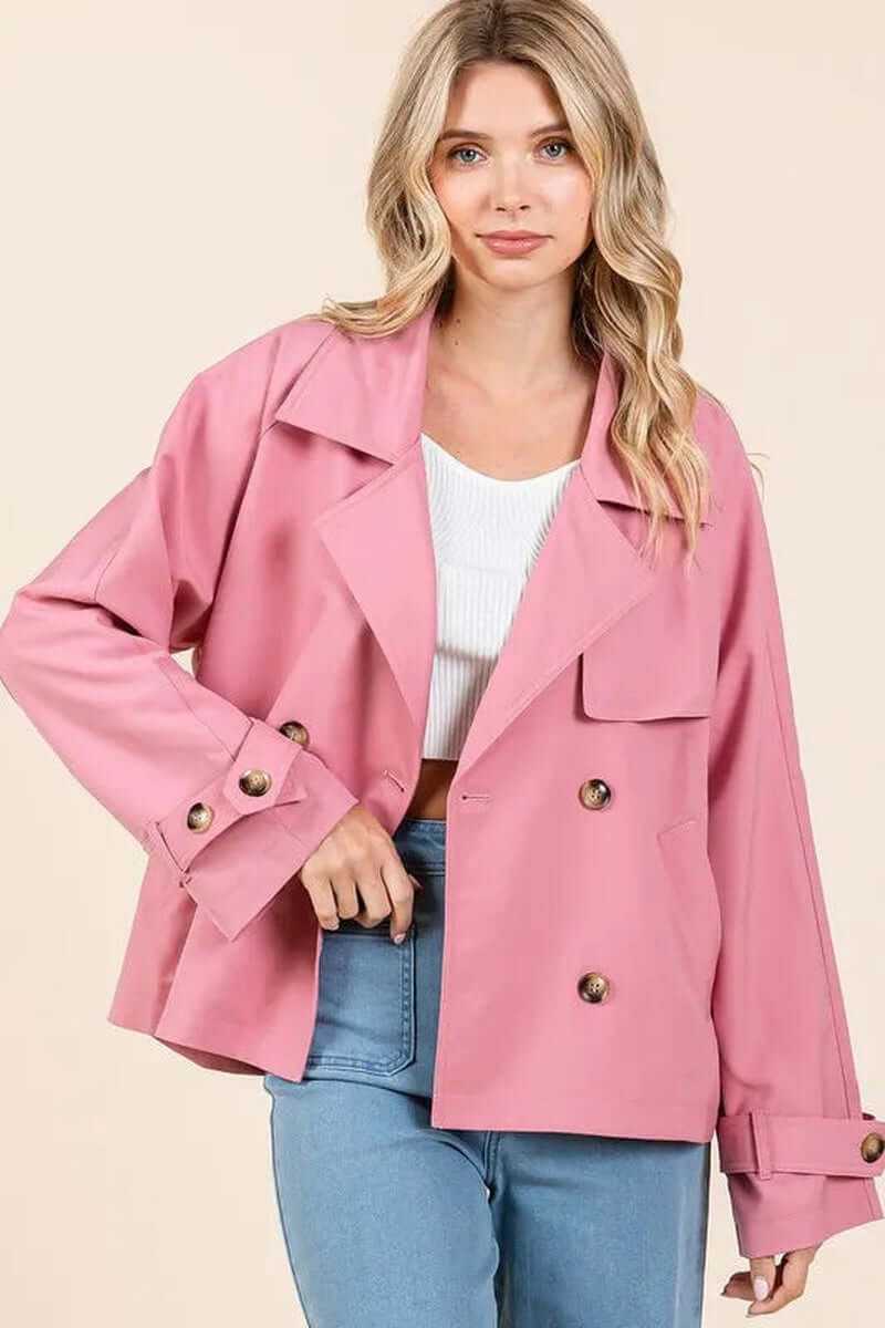 Elegant pink double-breasted trench coat jacket, featuring long sleeves and stylish buttons, worn casually with jeans.