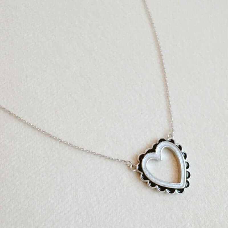 Elegant scallop edged heart necklace on a delicate chain, showcasing modern chic design in silver tone.