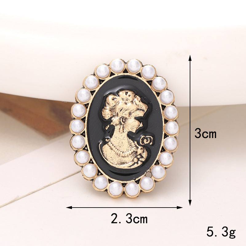 Elegant black and gold brooch with a pearl border, featuring a vintage woman's silhouette design.