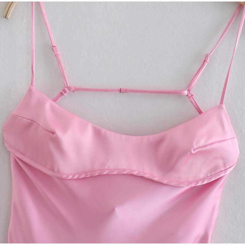 Close-up of pink satin camisole dress with thin straps, showcasing elegant design and soft fabric for summer wear.