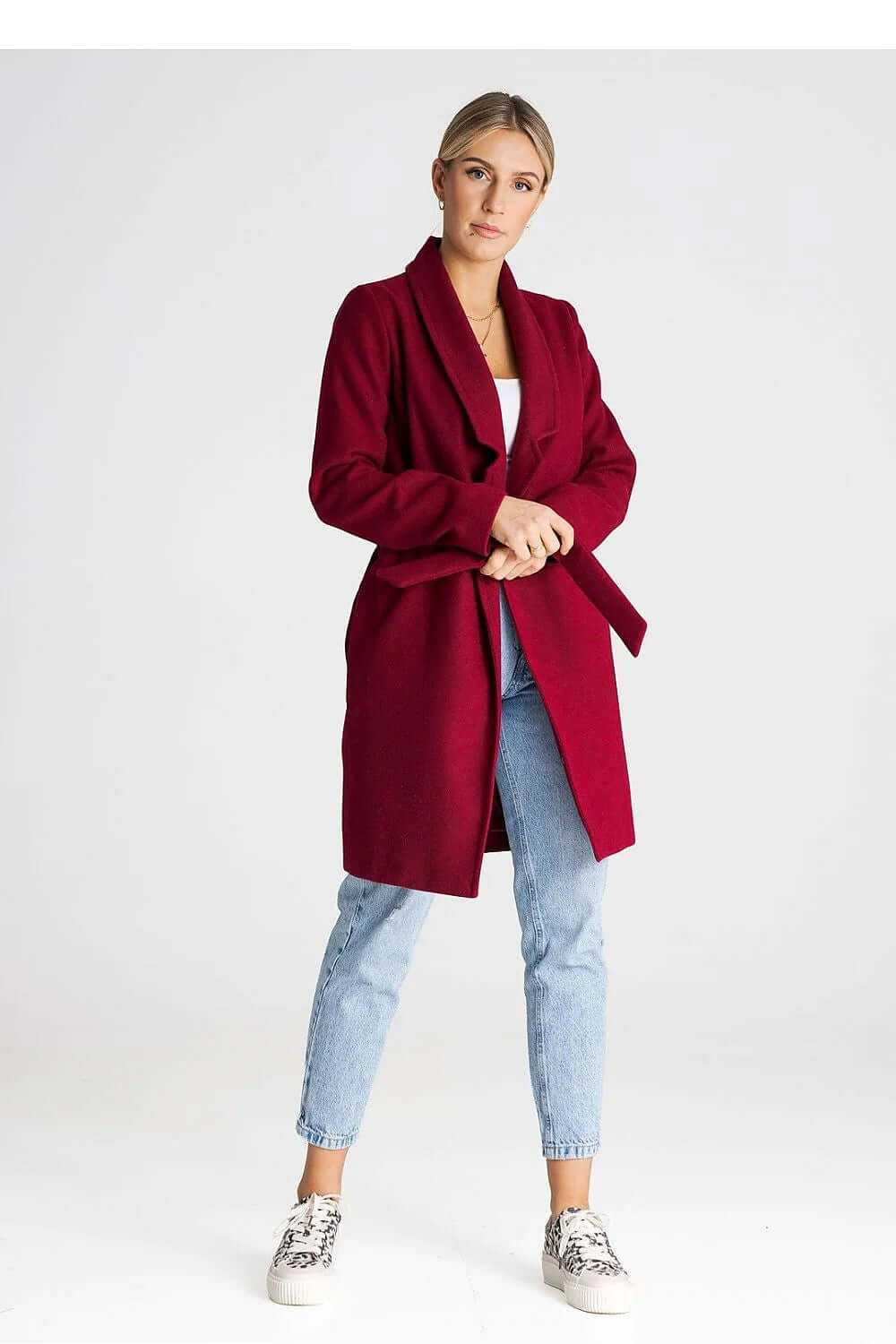 Figl Women’s Longline Winter Coat in burgundy, worn unbuttoned with a large collar and belt, paired with jeans.