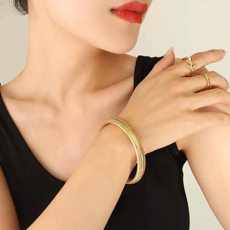 Close-up of a woman wearing a flexible slip-on gold plated elastic bangle, showcasing elegant style and comfort.