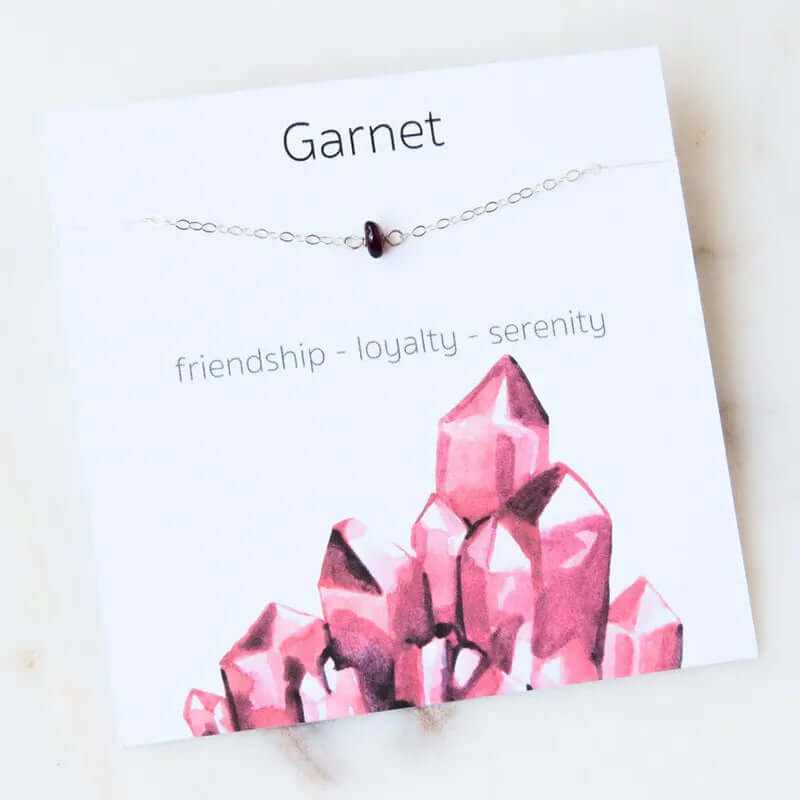 Garnet gemstone bracelet showcasing friendship, loyalty, and serenity on a decorative card with pink crystal design.