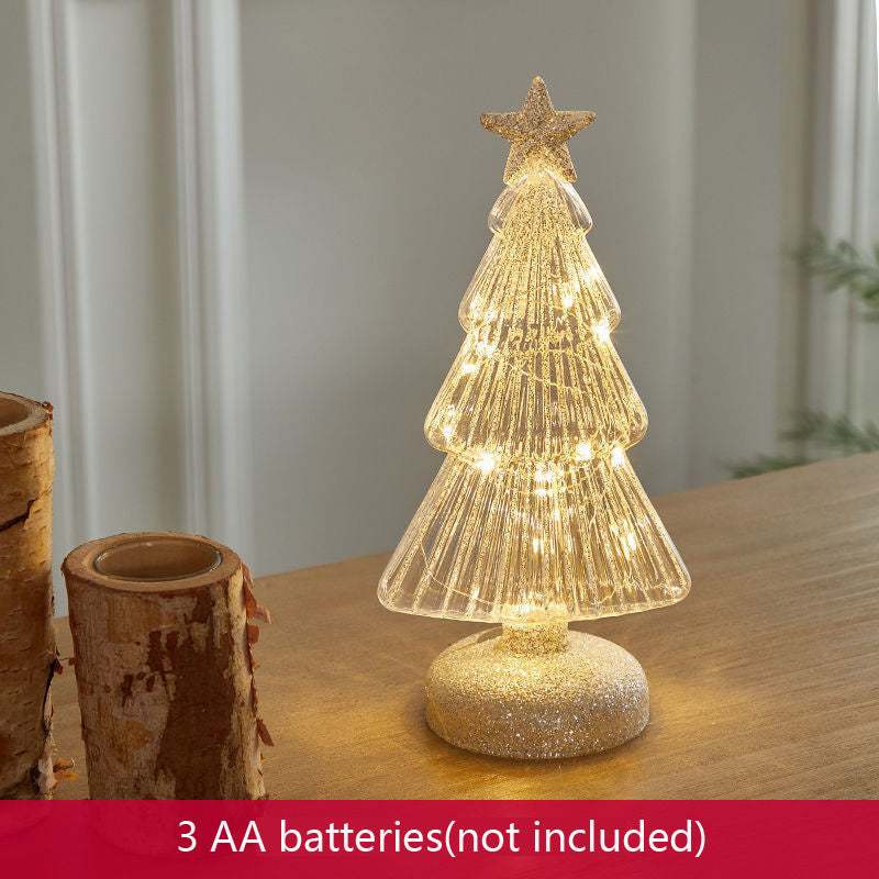 Christmas table decorations featuring a lit geometric glass Christmas tree with a star on top.
