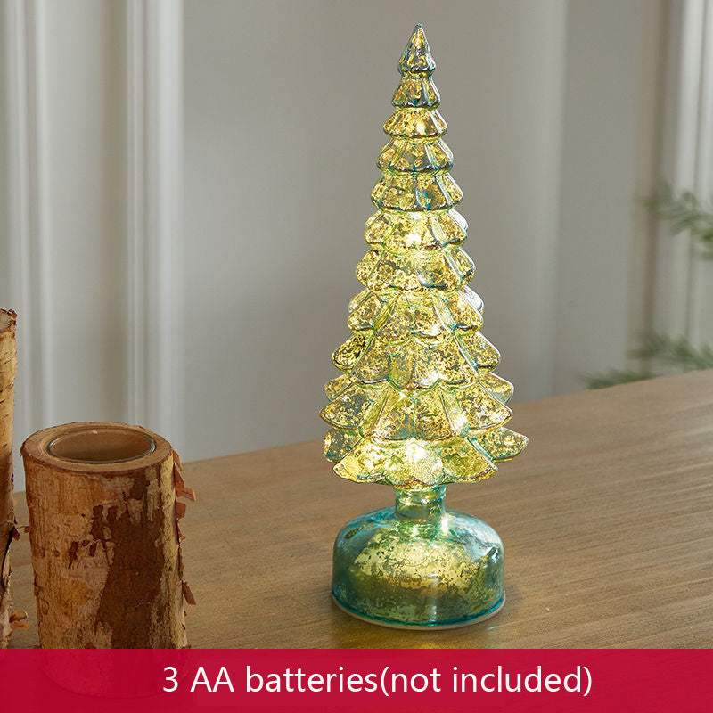 Christmas table decorations featuring a decorative glass Christmas tree in green and gold on a table.