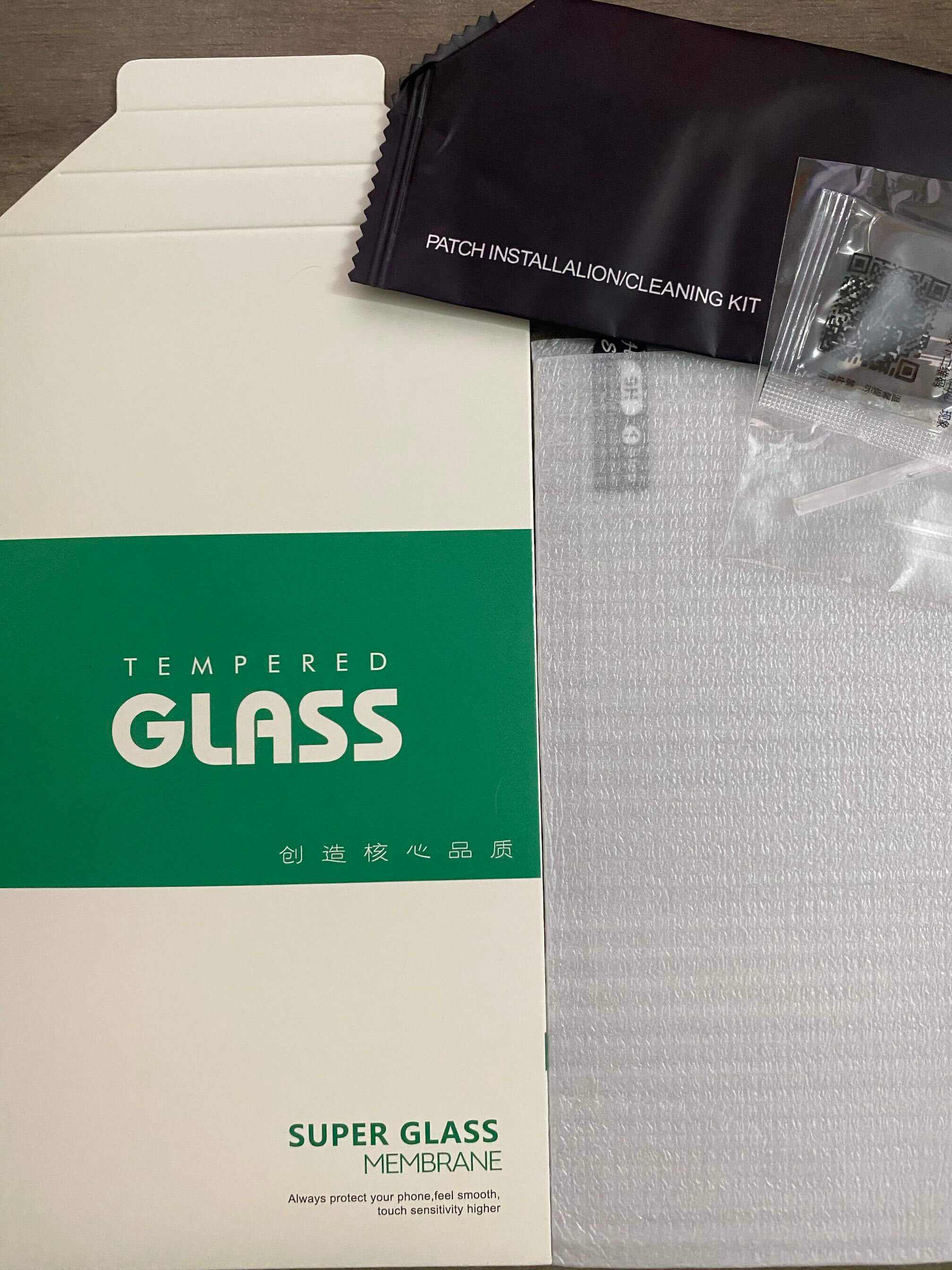 Tempered glass screen protector packaging with installation and cleaning kit included.