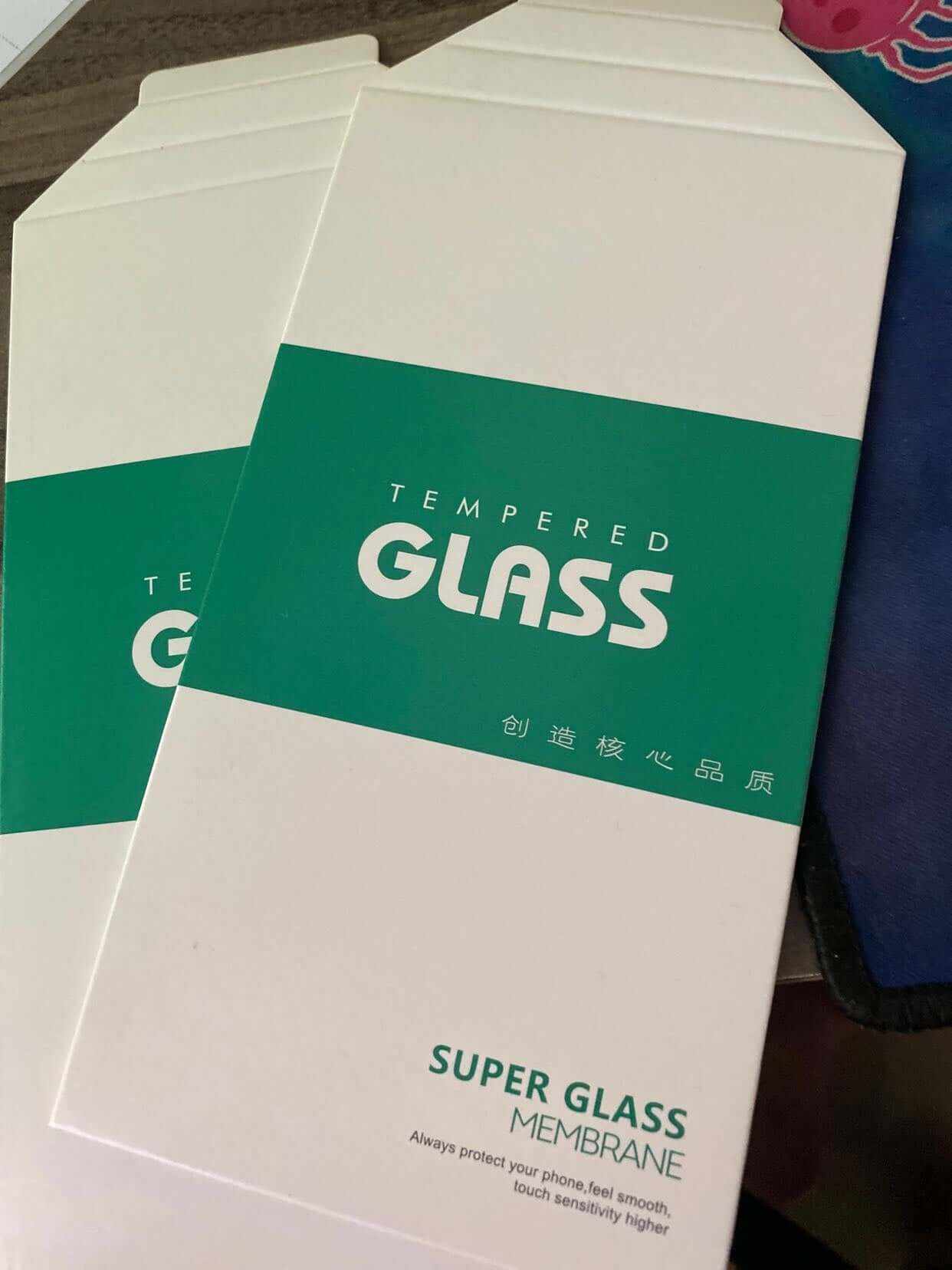Packaging of tempered glass screen protector showing product name and features.