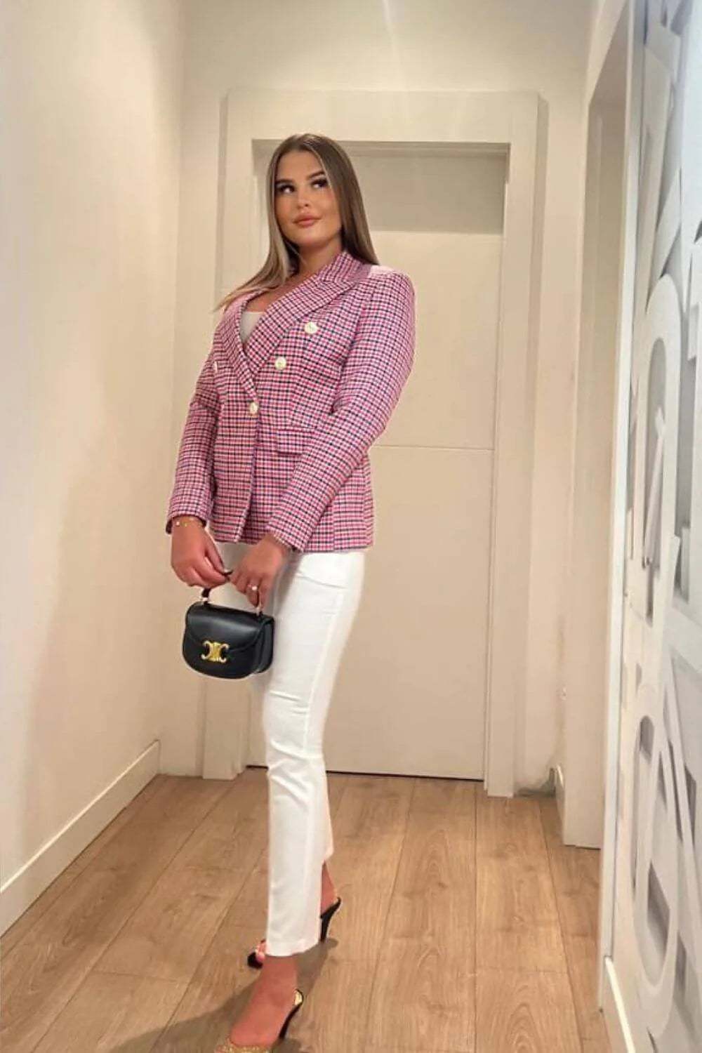 Elegant blazer in pink and white checkered pattern styled with white trousers and a black handbag.