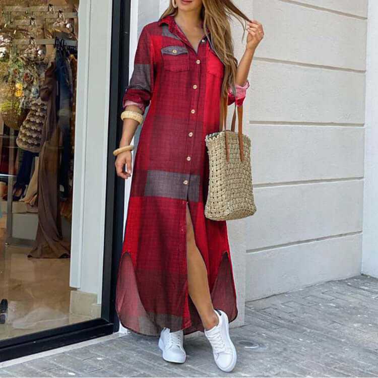 Stylish woman wearing a long red plaid shirt dress with a side slit, paired with white sneakers and a woven bag.