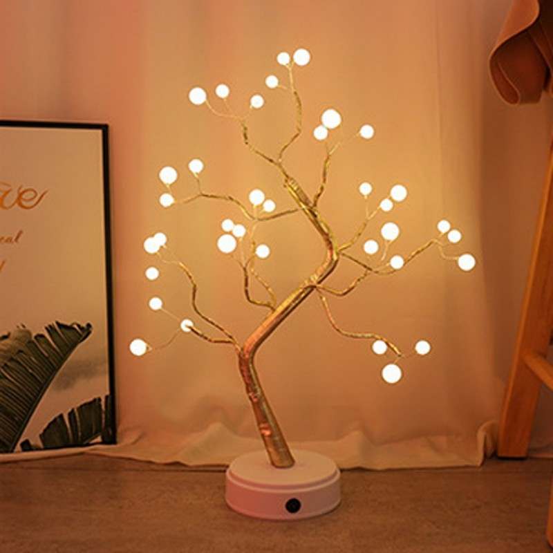 LED Christmas tree night light with warm white glowing orbs on branches and a white round base in cozy indoor setting