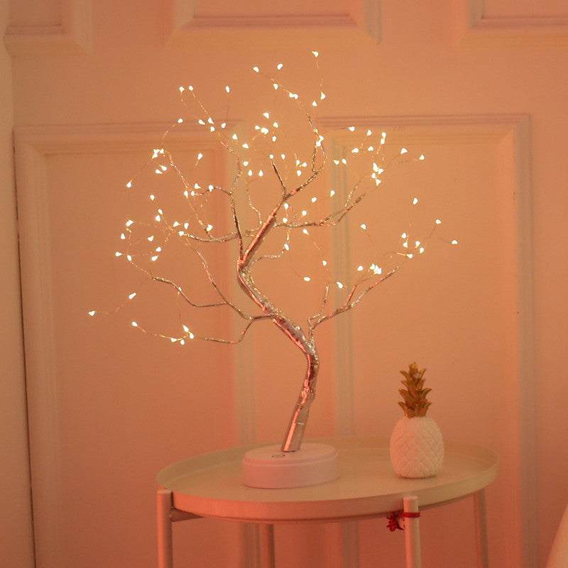 LED Christmas tree night light with warm white LED lights on a decorative branch design placed on a round table