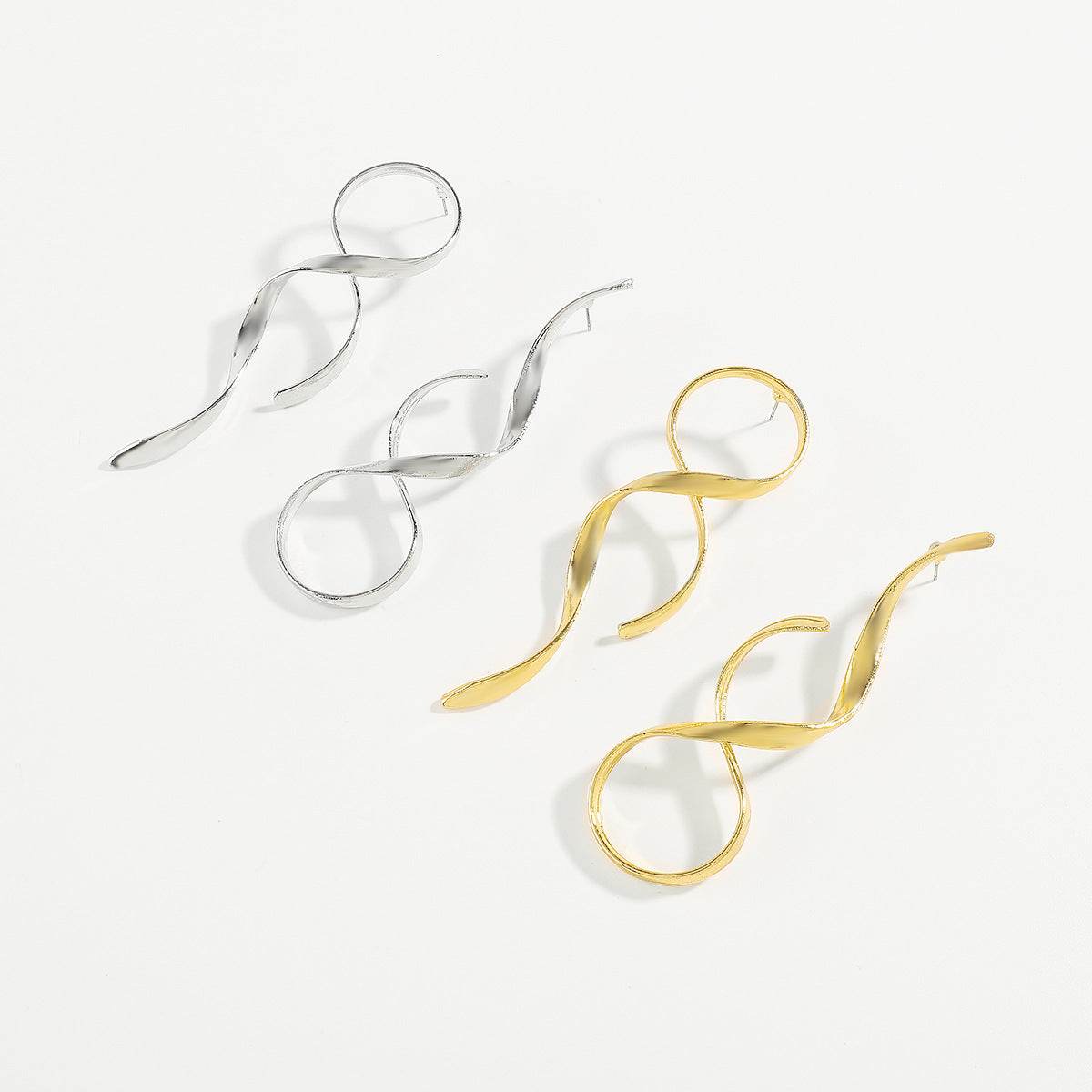 Asymmetric simple metal earrings in silver and gold colors with a twisted design