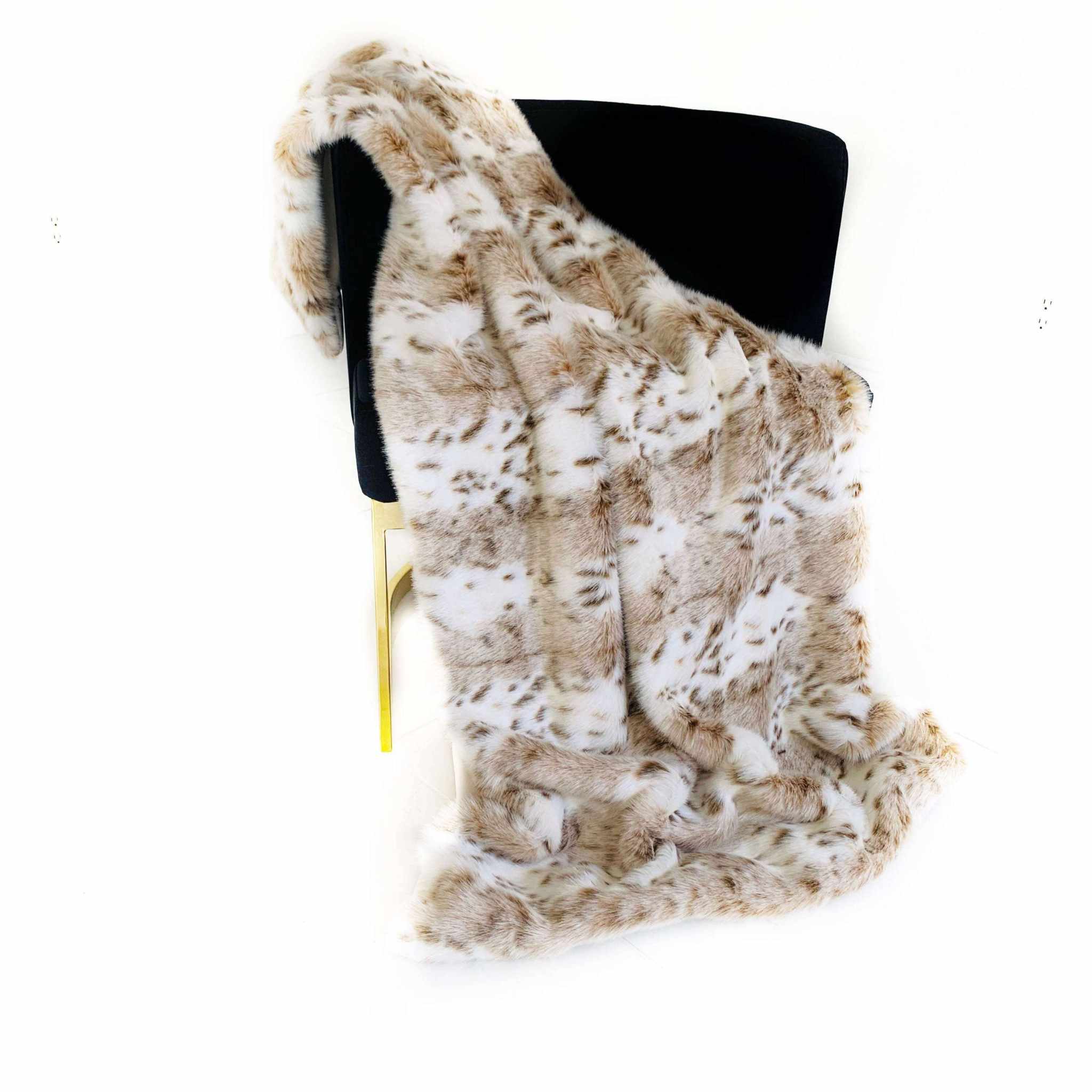 Luxury leopard faux fur throw blanket draped over a chair, showcasing its elegant taupe and black design.