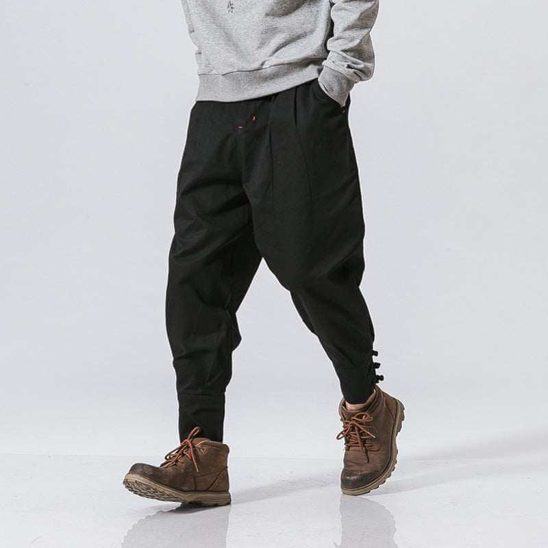 Men's black buckle casual pants made from cotton blend with button placket and tapered leg design.