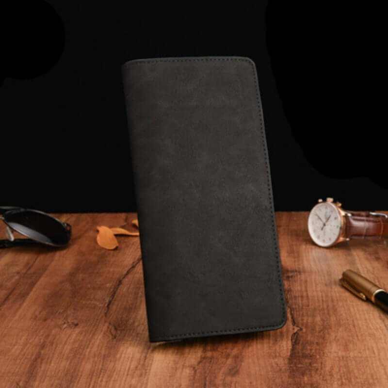 Men's compact black genuine leather wallet on wooden table, showcasing elegant design and durable materials.