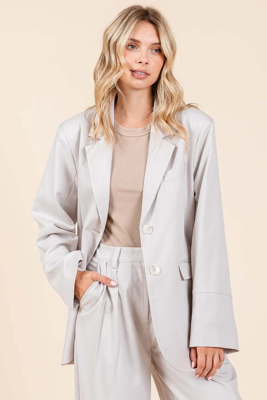Woman wearing a light gray boyfriend fit blazer jacket with relaxed styling and a modern look.