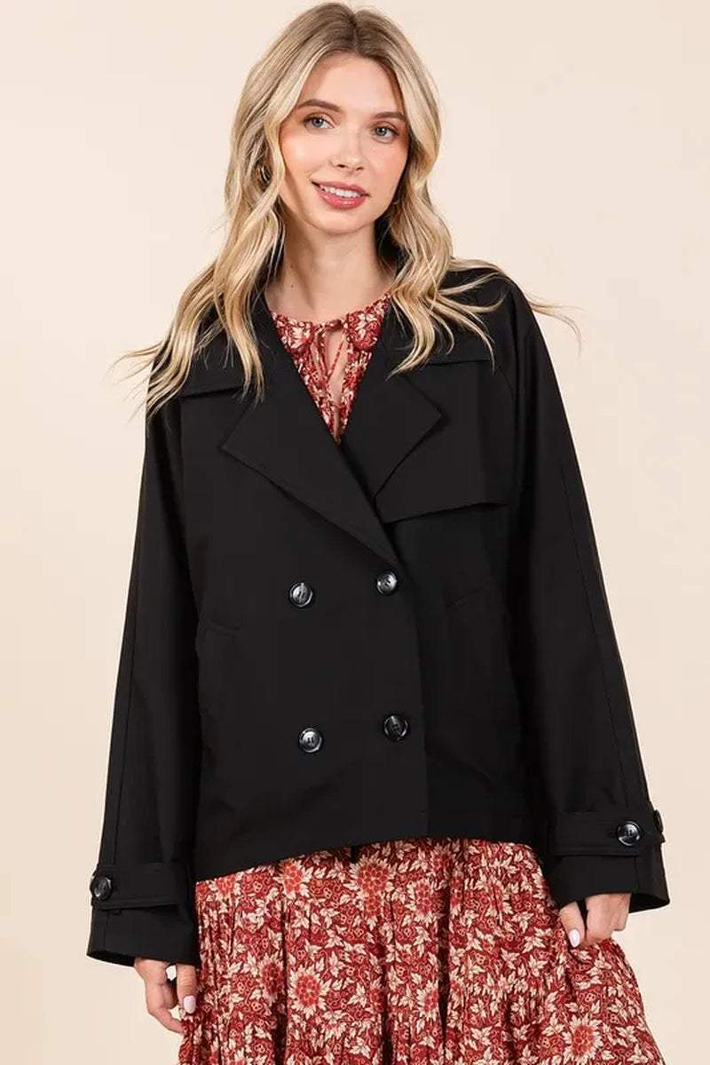 Woman wearing black double breasted trench coat jacket over floral dress