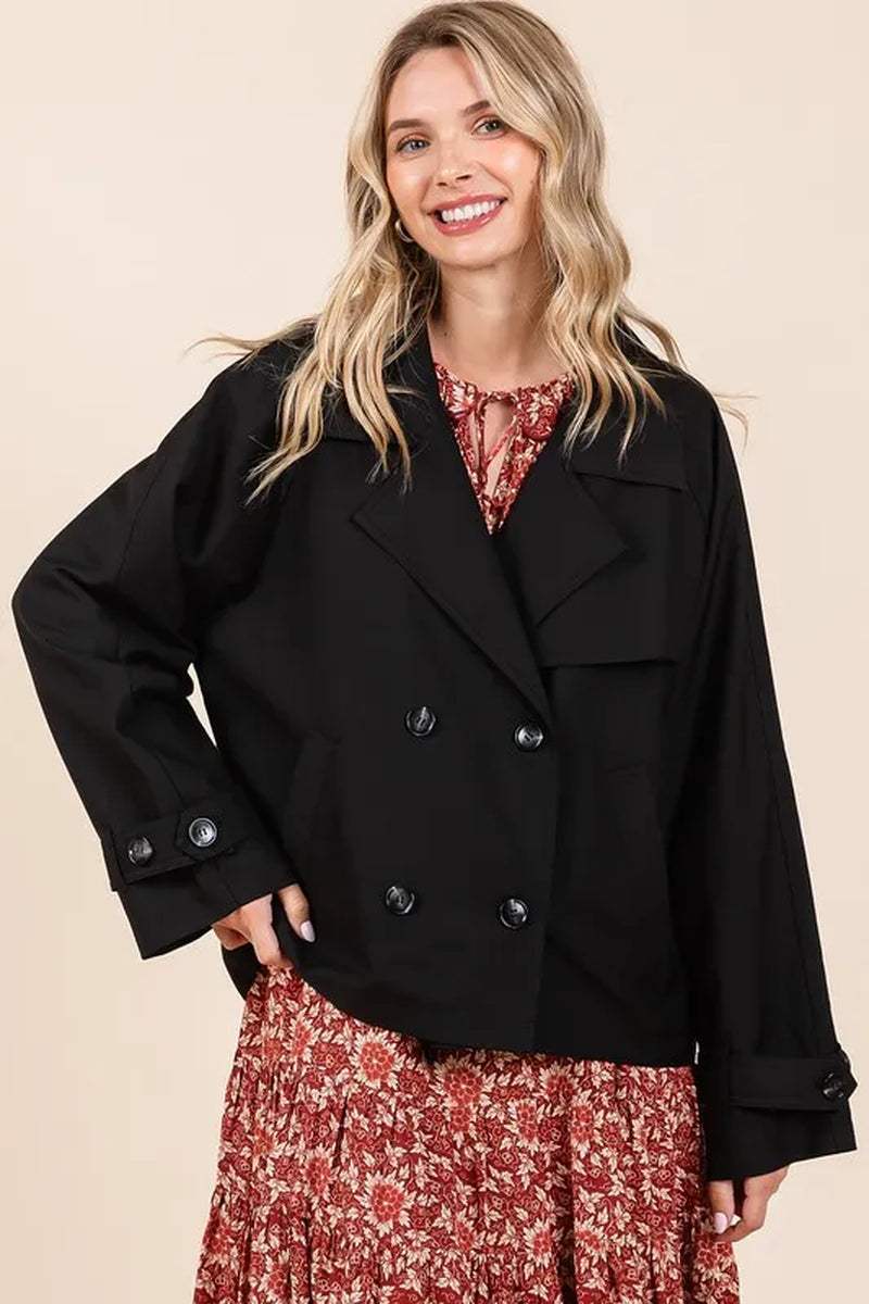 Black double breasted trench coat jacket with long sleeves on smiling woman in floral dress