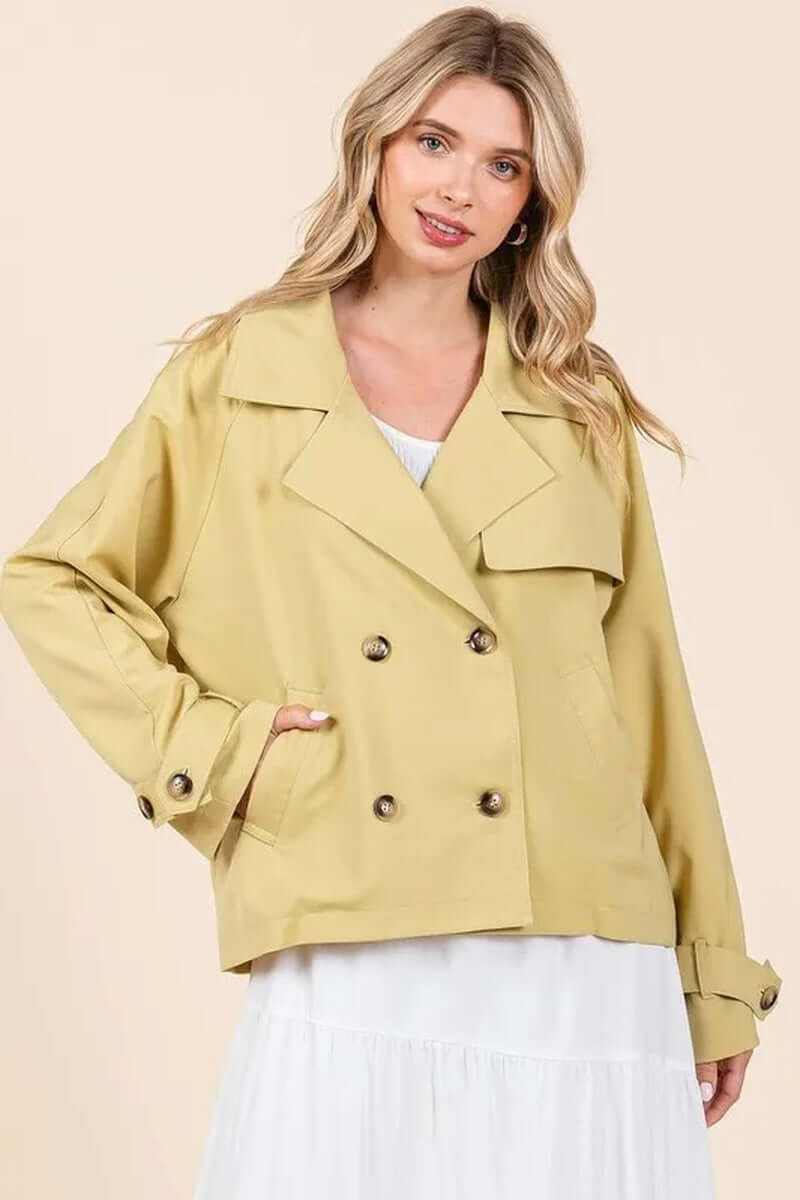 Model wearing a double-breasted long sleeve trench coat jacket in soft yellow, perfect for transitional weather.