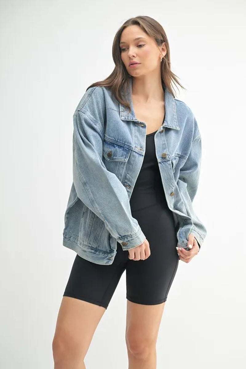 Stylish woman wearing a boxy-cut denim jacket over a black outfit, showcasing a relaxed fit and modern design.