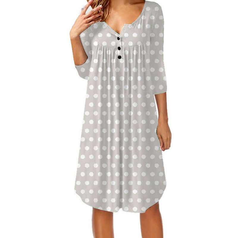 Woman wearing a loose mid-length dress with white polka dot print and black buttons, featuring three-quarter sleeves and a semi-open collar