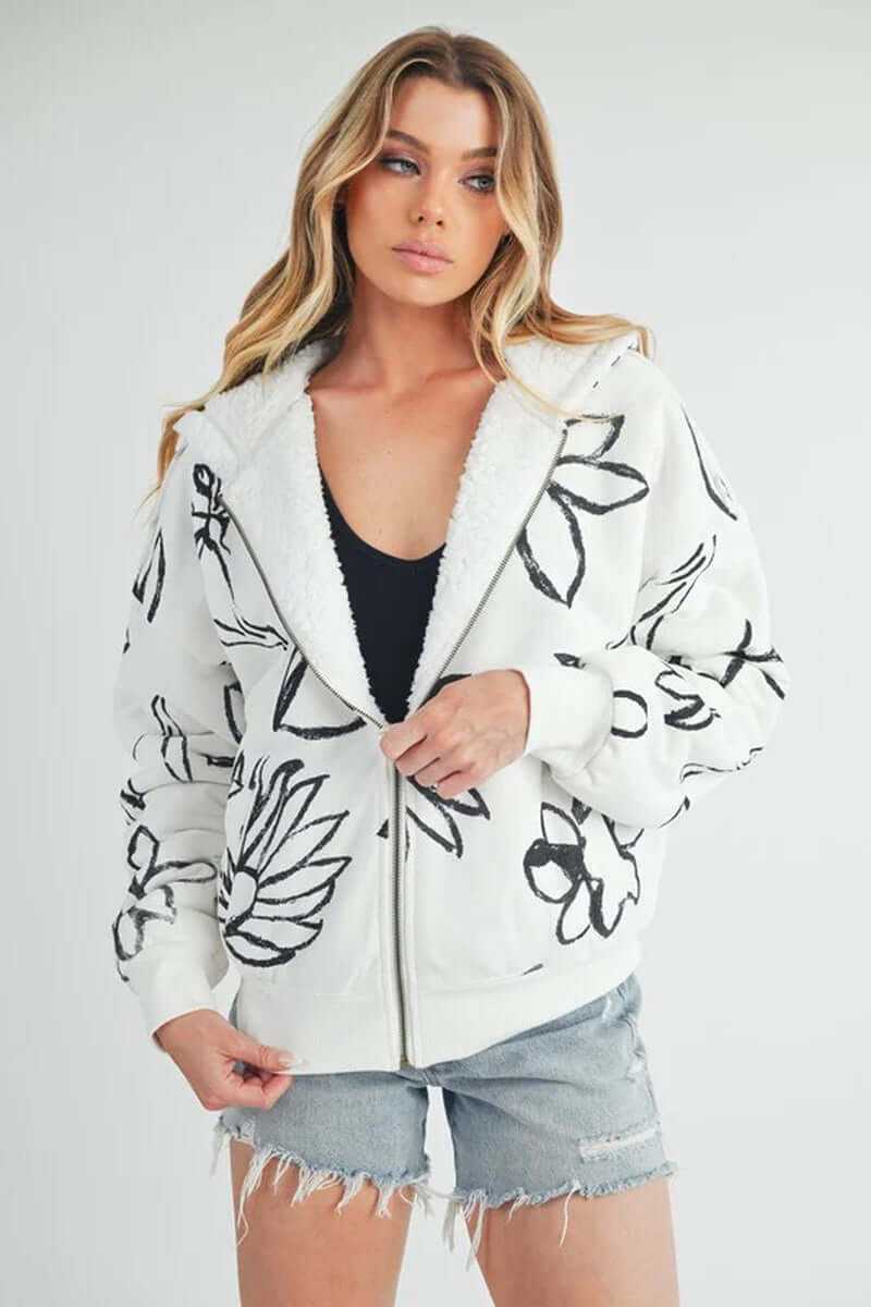 Model wearing the Oita jacket, featuring floral print, front zip closure, and cozy sherpa lining.