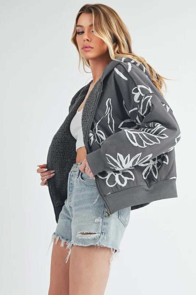 Model wearing the Oita jacket, a bomber-inspired design with floral prints and sherpa lining, paired with denim shorts.
