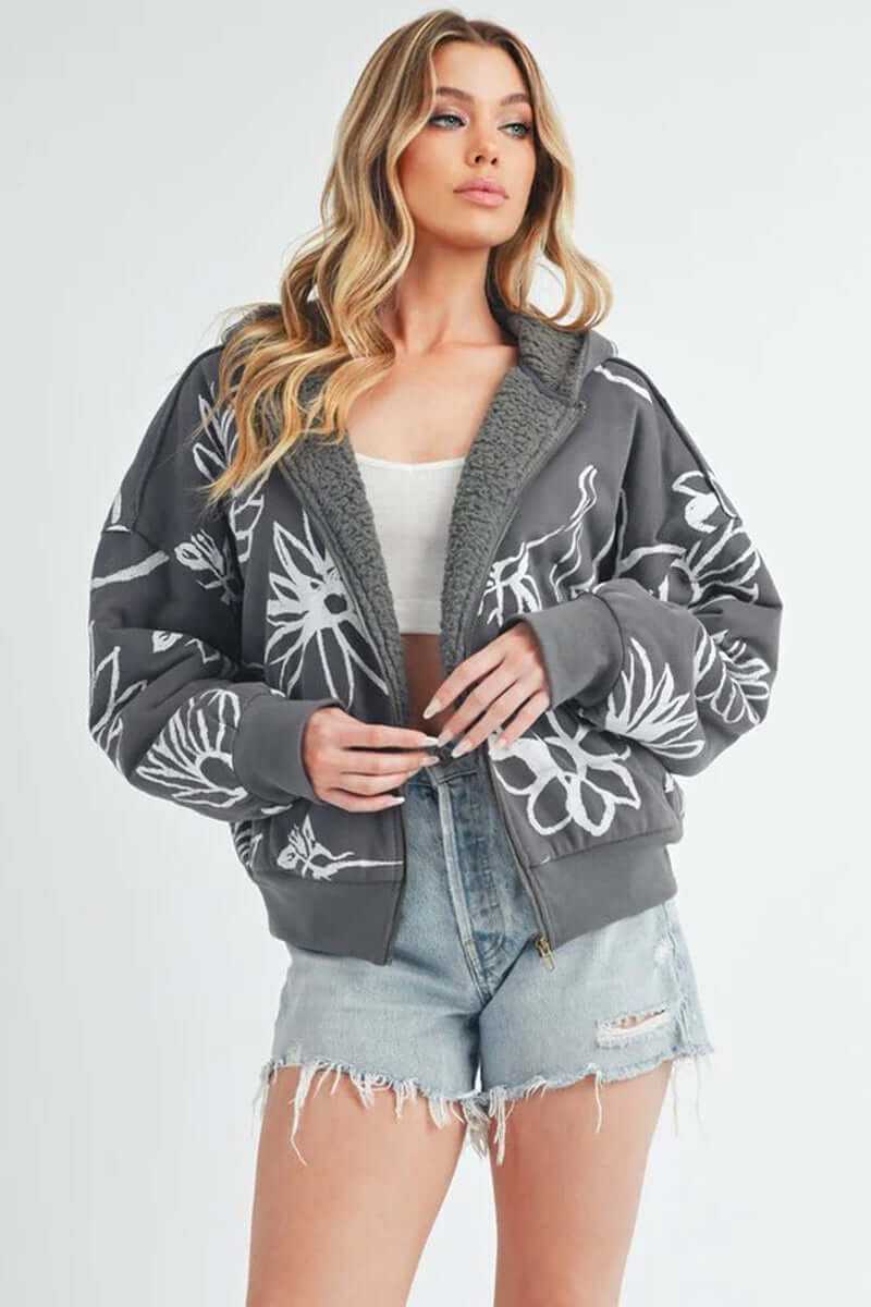Model wearing the Oita jacket, a cozy bomber-style jacket with floral print, oversized fit, and sherpa lining.