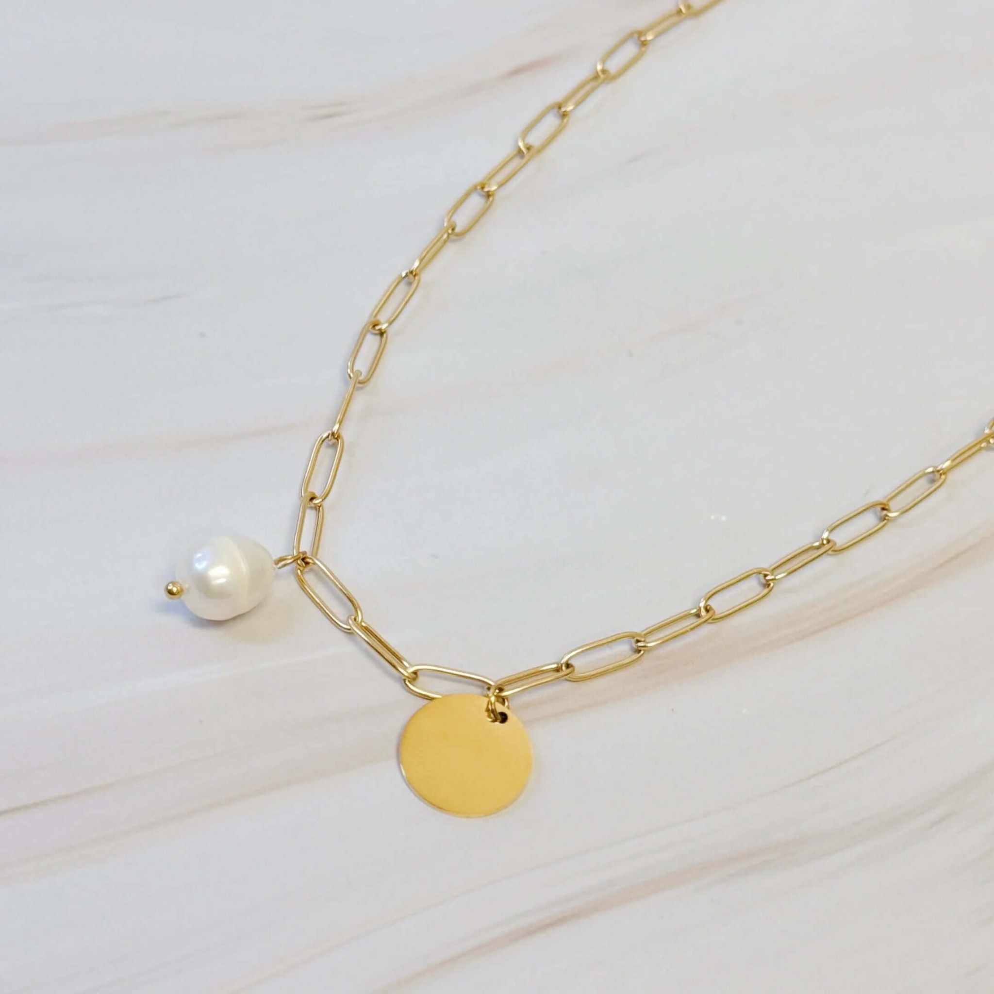 Freshwater pearl and gold disc chain necklace on a marble background, elegant and trendy jewelry for any occasion.