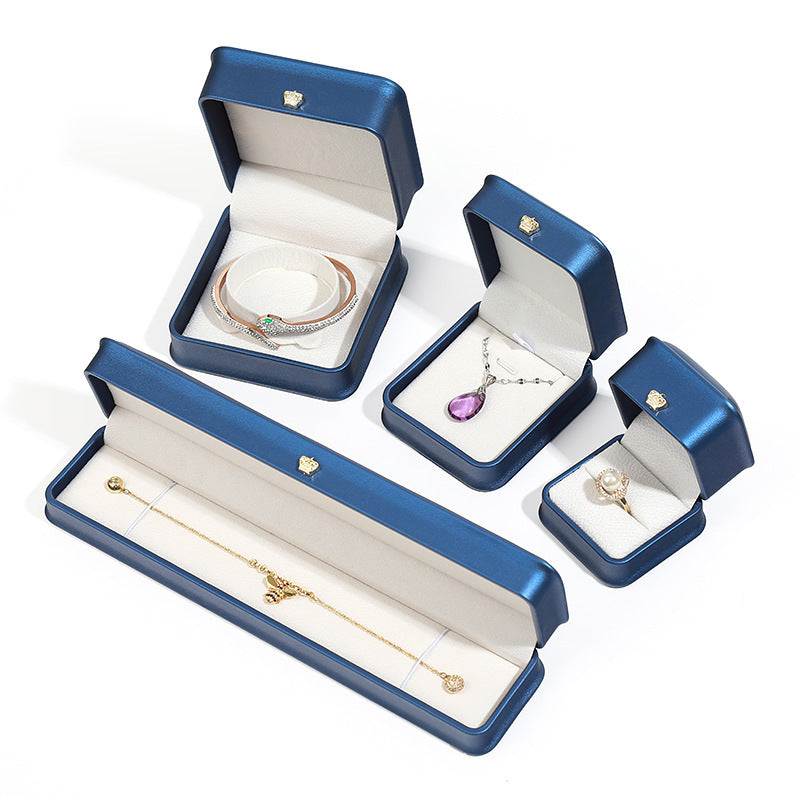 Elegant pendant and lace bracelet display case set in blue, showcasing various jewelry boxes for rings, necklaces, and bracelets.