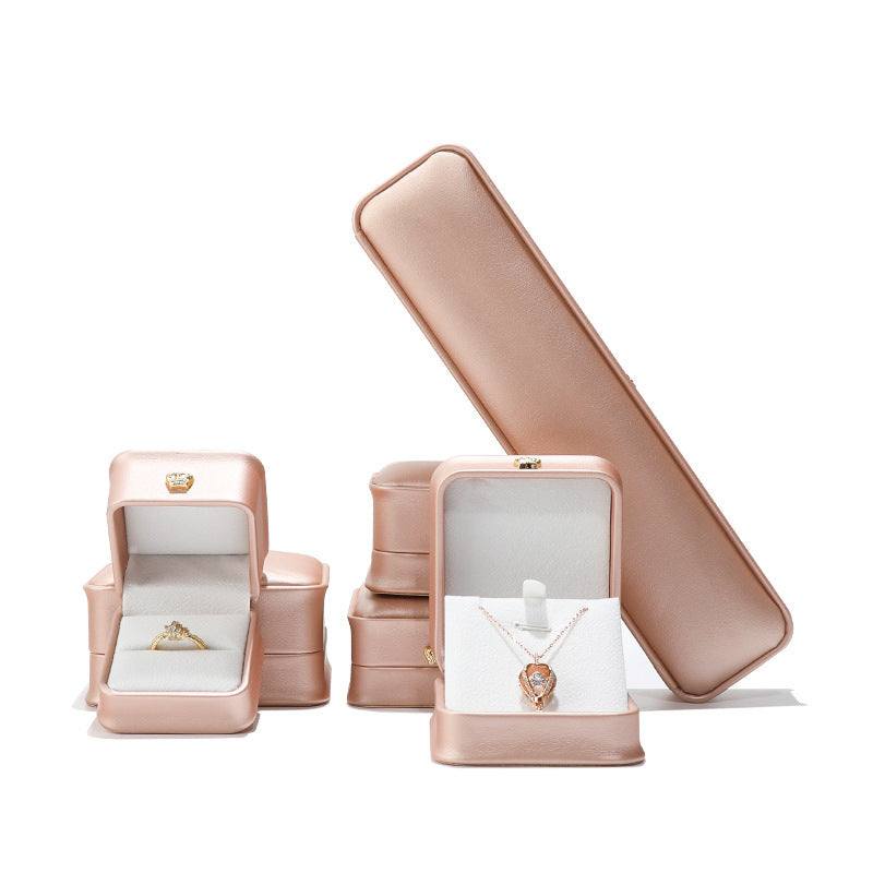 Elegant rose gold jewelry display case featuring assorted boxes for rings, necklaces, and bracelets.