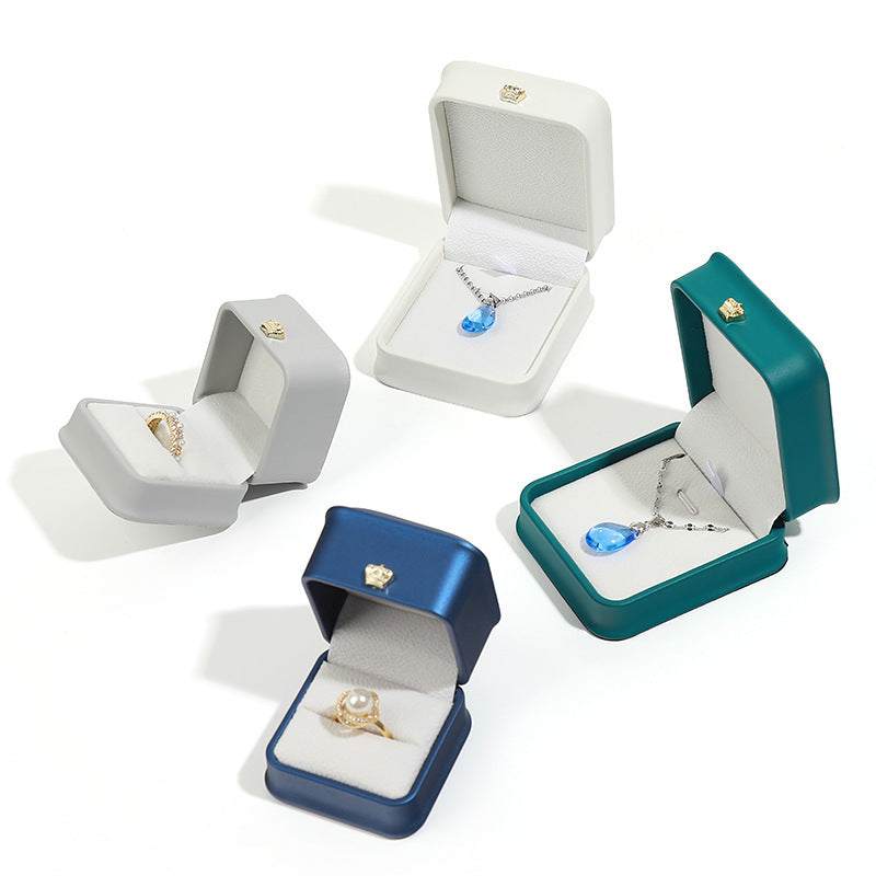 Assorted pendant and bracelet display cases in various colors: white, teal, navy, and gray for jewelry storage.