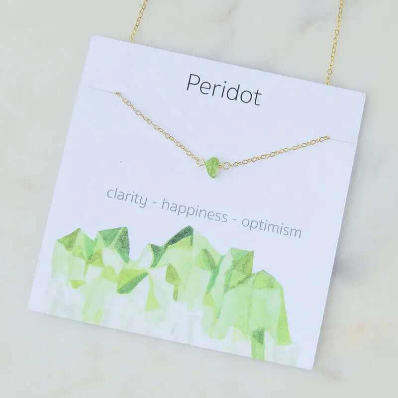Peridot necklace on display card highlighting clarity, happiness, and optimism with a green gemstone.